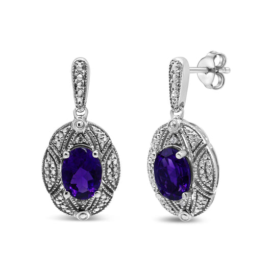 Pair of white metal earrings with oval purple gemstones surrounded by intricate detailing and small round white gemstones, shown from the front and side angles.