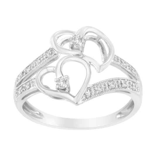 White metal ring with two open heart shapes, each set with a prong-set brownish round gemstone, and a band decorated with micro-pave brownish round gemstones, shown from a front angle.