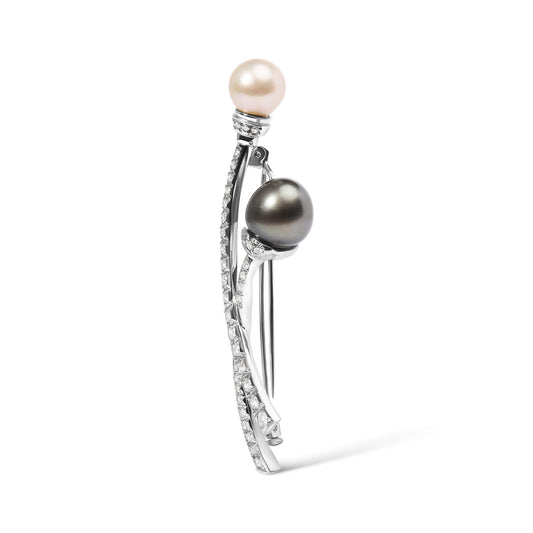 Side view of a white metal brooch with two pearls, one white and one dark, each accented with small white gemstones along curved metal stems.