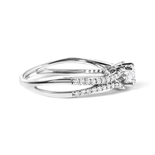 Side angled view of a white metal ring with a single round gemstone in a four-prong setting and multiple smaller round gemstones in a shared prong setting along the band.