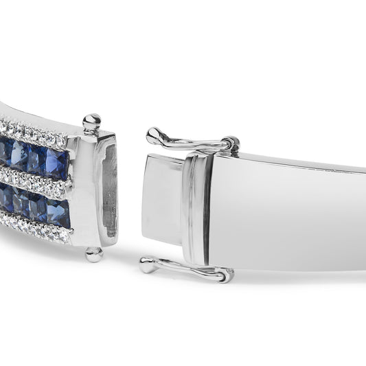 Close-up side angle of white metal bracelet clasp featuring rows of channel-set blue square gemstones and prong-set round white gemstones.
