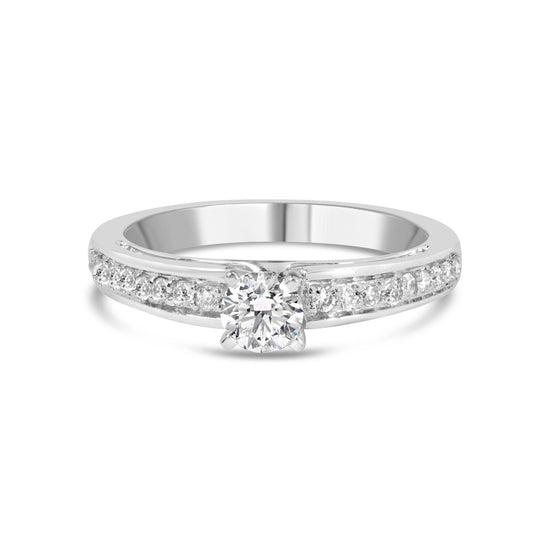 Front angle view of white metal ring with a single round white gemstone in 4-prong setting and additional round white gemstones in shared prong setting along the band.