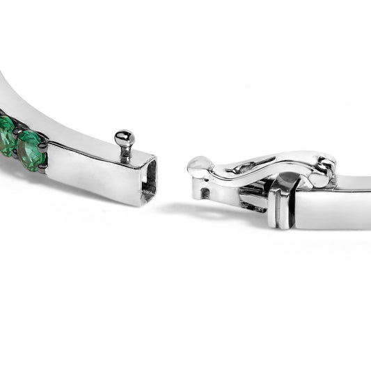 Close-up image of a white metal bracelet clasp with green round gemstones and one white oval gemstone, shown from a side angle on a white background.