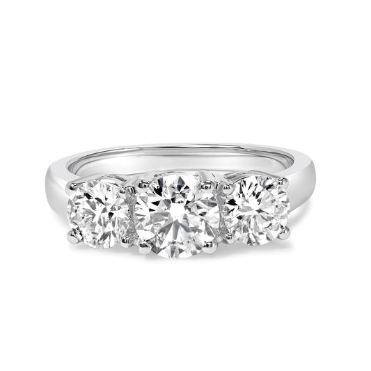 Front angled view of a white metal ring featuring three round white gemstones in four-prong settings.
