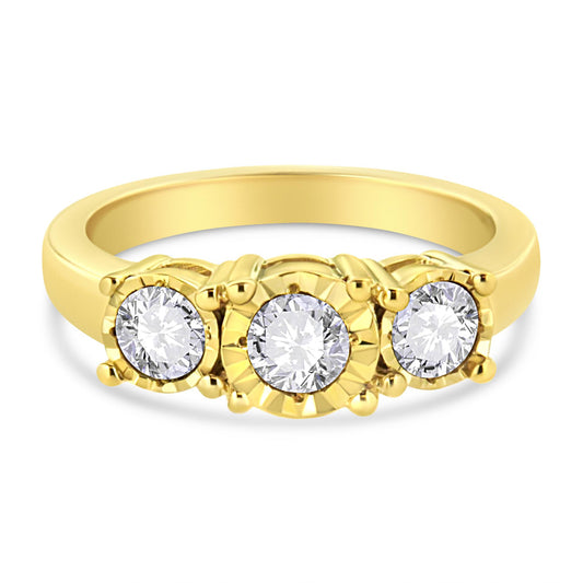 Close-up front angle of a yellow ring with three round white gemstones in miracle settings, the center gemstone featuring a decorative bezel.