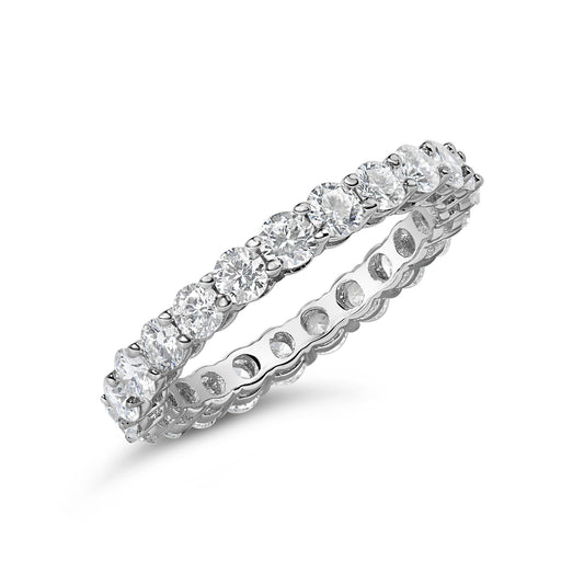 White metal eternity ring with round white gemstones in shared prong setting, shown at an angle on a white background.