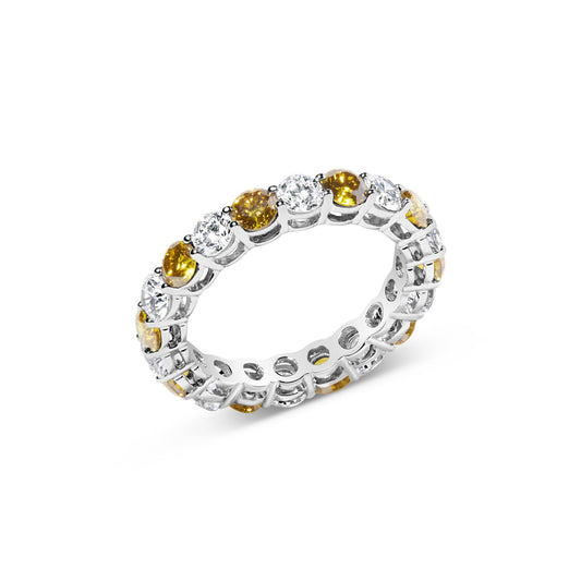 White metal ring viewed at an angle, featuring alternating round yellow and white gemstones in prong settings encircling the band.