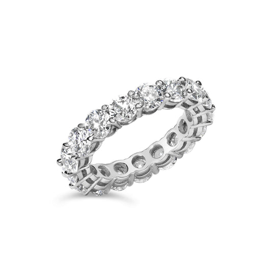 White metal eternity band ring with round white gemstones in shared prong setting, shown at a slight angle on a white background.