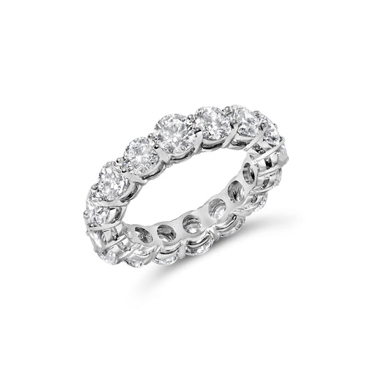 White metal eternity ring with round white gemstones in prong settings, shown at an angled close-up.