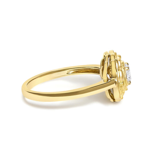 Close-up side angle of a yellow metal ring with a round white gemstone in a 4-prong setting.