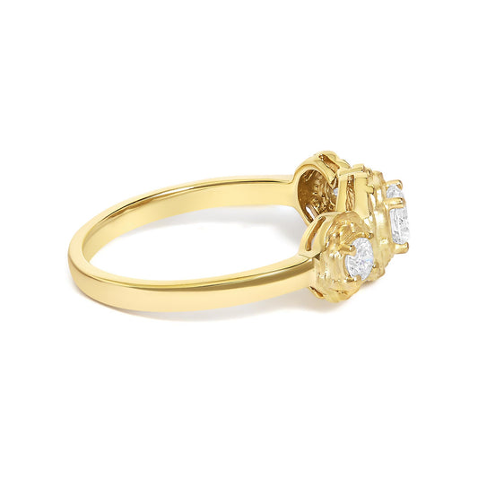 Close-up side angle of a yellow metal ring featuring one round white gemstone in a prong setting flanked by two smaller round white gemstones in prong settings.