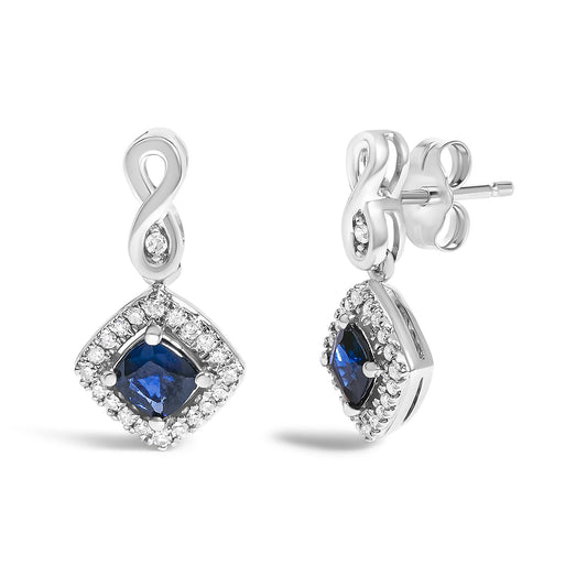 Front and side view of white metal earrings with an infinity-shaped top and a square-shaped drop featuring a blue gemstone center surrounded by small white gemstones.