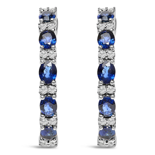 Front view of pair of white metal earrings featuring alternating oval blue gemstones and round white gemstones in shared prong and 4-prong settings.