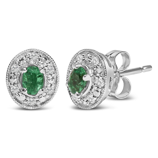 Close-up angled view of white metal stud earrings featuring oval green gemstones in the center, surrounded by a halo of small round white gemstones in a pave setting.