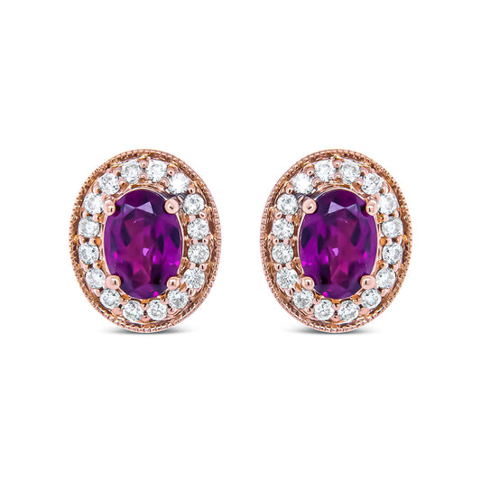 Close-up front view of a pair of rose metal oval earrings featuring a large oval red gemstone surrounded by a halo of round white gemstones in prong settings.