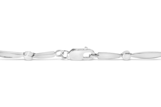 Close-up side view of a white metal bracelet with smooth, elongated oval links and a clasp, featuring a section with three round white gemstones in a channel setting.