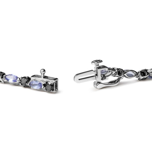 Close-up angled view of a white metal bracelet clasp featuring alternating marquise-shaped blue gemstones and round black gemstones in prong settings.