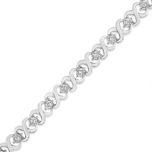 White metal bracelet with round white gemstones set in a miracle setting along a wavy linked design, shown in a diagonal flat lay angle.