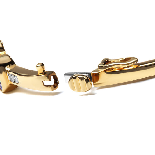 Close-up angled view of an open yellow metal bracelet clasp featuring white round gemstones set in a channel setting and blue oval gemstones in bezel setting.