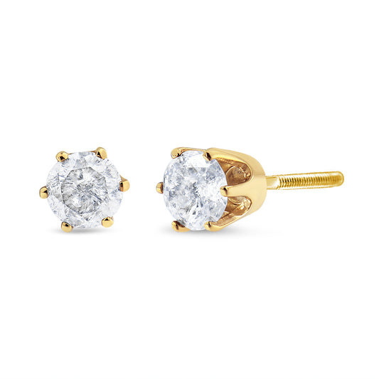 Close-up angled view of yellow metal stud earrings with two round white gemstones in six-prong settings.