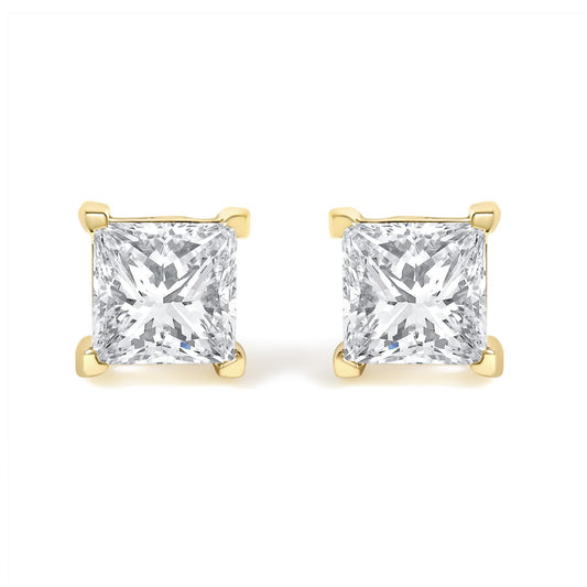 Front view of a pair of yellow metal stud earrings each featuring a princess-shaped white gemstone in a four-prong setting.