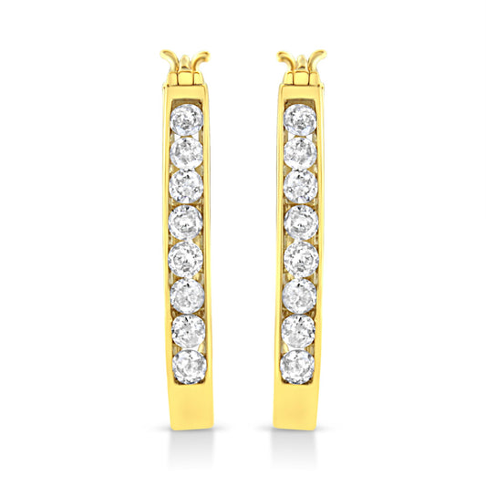 Front-facing view of a pair of yellow metal hoop earrings with a vertical row of round white gemstones set in a channel setting.
