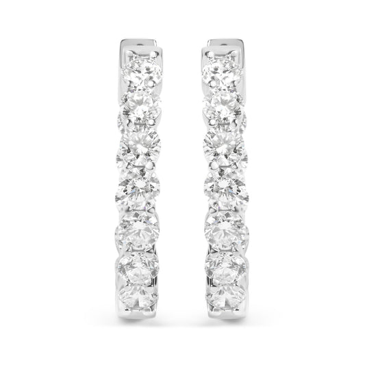 Front view of a pair of white metal hoop earrings set with multiple round white gemstones in a shared prong setting.