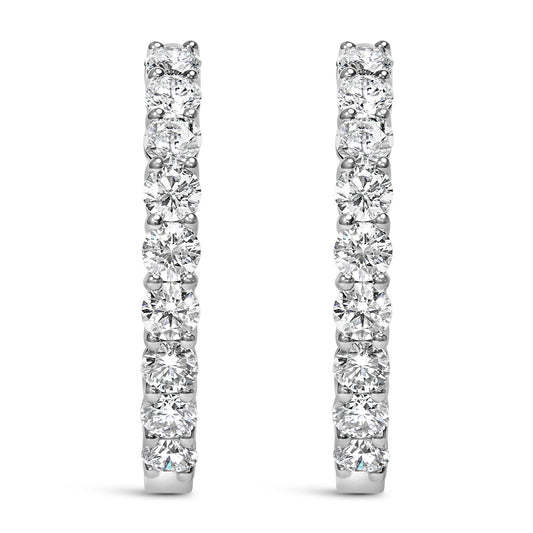 Front view of white metal hoop earrings set with round white gemstones in shared prong settings.