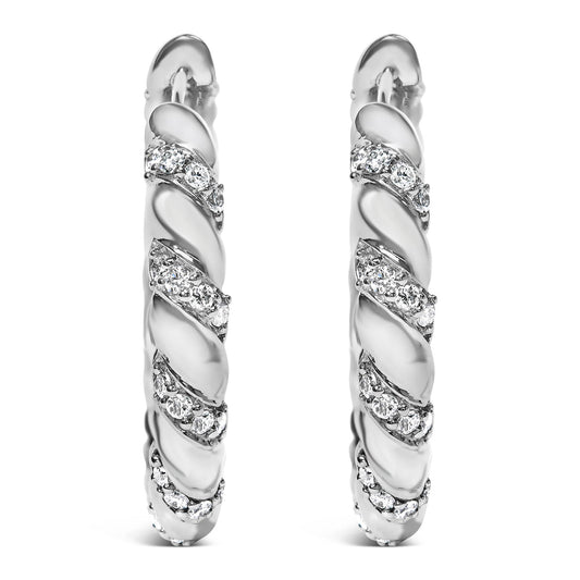 Front view of a pair of white metal hoop earrings with a twisted design featuring multiple rows of round white gemstones in prong settings.