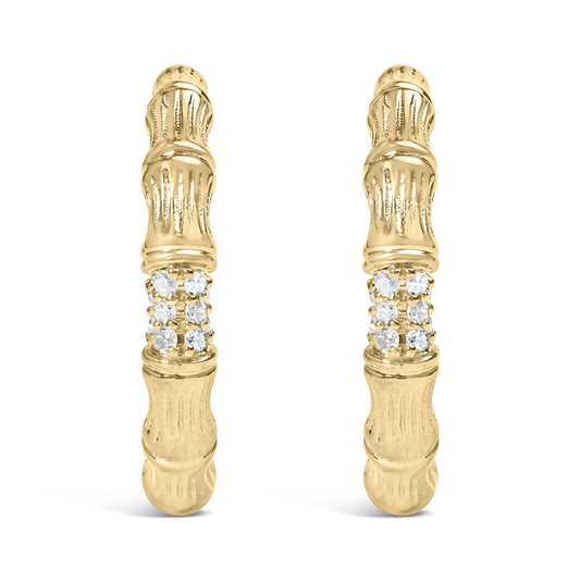 Front facing shot of a pair of yellow metal earrings with textured design and a cluster of round white gemstones in prong settings near the center.