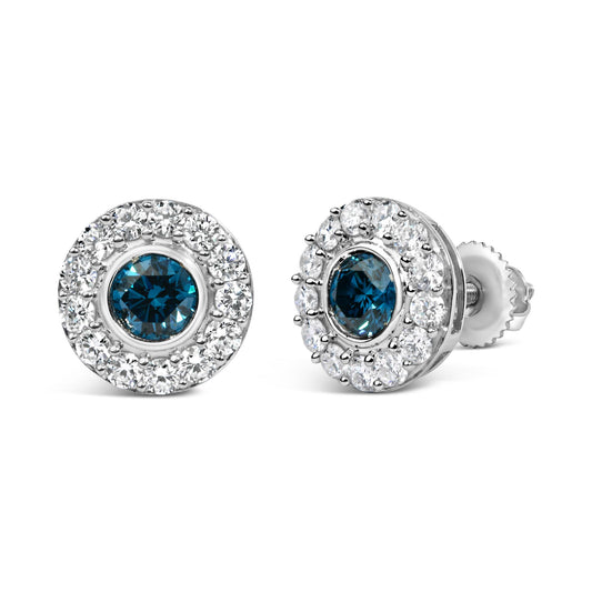 Close-up front view of a pair of white metal round stud earrings featuring a central round blue gemstone surrounded by a halo of round white gemstones in prong settings, shown on a white background.