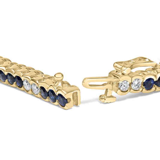 Close-up angle of an open yellow metal bracelet featuring alternating round blue and white gemstones in bezel settings.