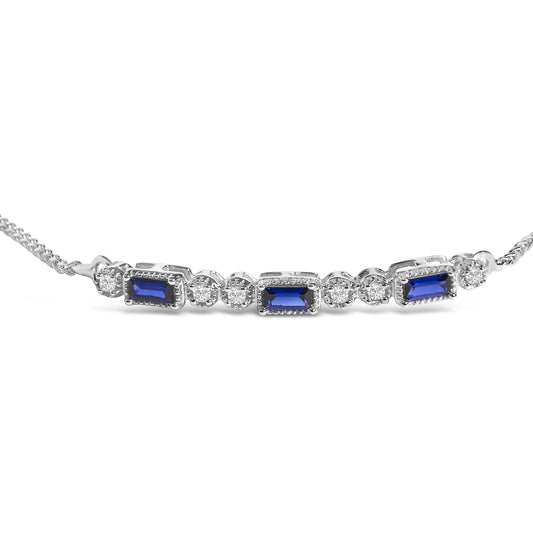 Close-up front angle of a white metal bracelet with alternating rectangular blue gemstones and round white gemstones in prong settings.