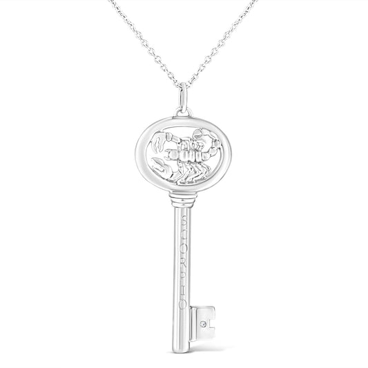 Front facing shot of a white metal key-shaped necklace pendant with a scorpion design inside the round top and one brownish round gemstone in a bezel setting near the bottom.