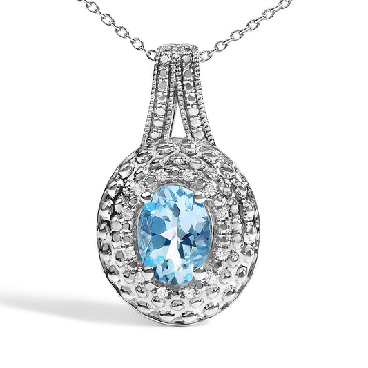 Close-up front angle of white metal necklace pendant featuring an oval blue gemstone prong-set in the center, surrounded by small round white gemstones in a pave setting.