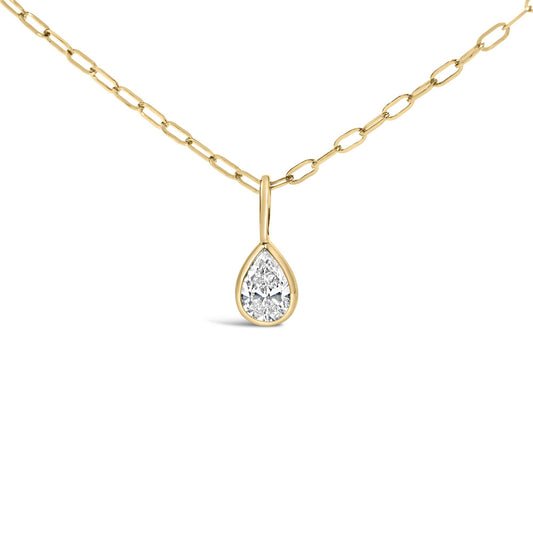 Close-up front view of a yellow metal necklace with a pear-shaped white gemstone in a bezel setting pendant.