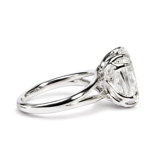 Close-up side angle of a white metal ring featuring an oval-shaped white gemstone in a double claw prong setting.