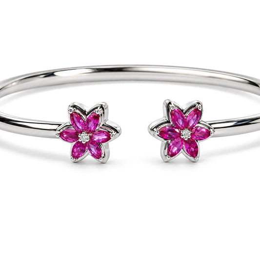 Close view of sterling silver lab created ruby and diamond bangle showcasing floral ends with diamond centers on white background
