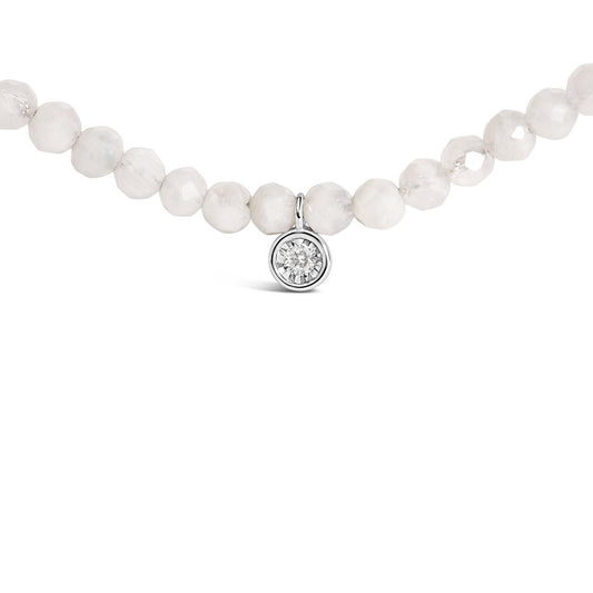 Close-up front view of a white necklace made of round white gemstones with a small round white gemstone pendant set in white metal.