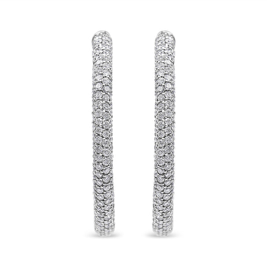 Front-facing shot of a pair of white metal hoop earrings set with multiple rows of round white gemstones in a pave setting.
