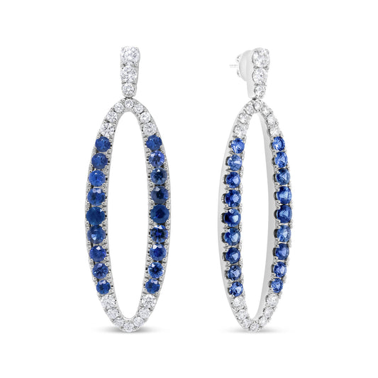 Pair of white metal oval hoop earrings with round prong-set white and blue gemstones, shown from a front and angled side view.