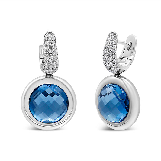 Pair of white metal earrings with round blue gemstones bezel set, topped with curved sections encrusted with small white gemstones, shown from a front and angled side view.
