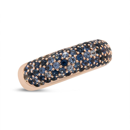 Close-up angled view of a rose-colored ring encrusted with multiple round blue gemstones in prong settings.