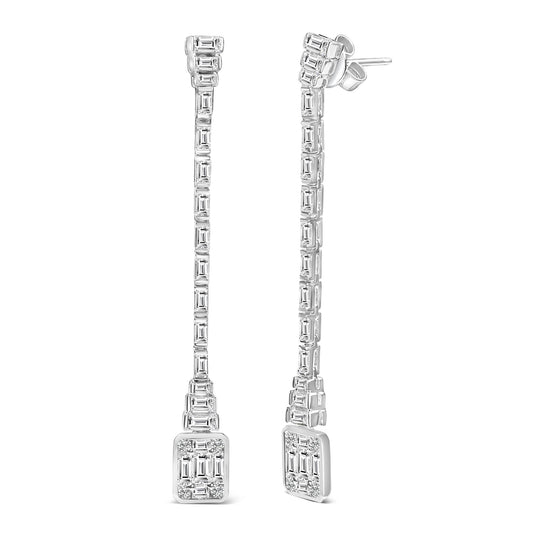 Front angled view of a pair of white metal long drop earrings with round gemstones in bezel setting at the tops and white baguette gemstones in channel settings arranged along the length, ending in a square cluster of baguette and round gemstones.