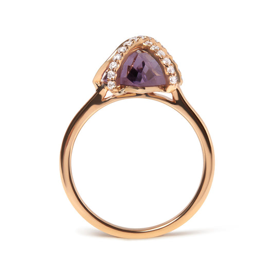 Front-facing view of a rose-colored ring featuring a purple gemstone in a marquise shape with tension setting, surrounded by a pave of small white round gemstones.