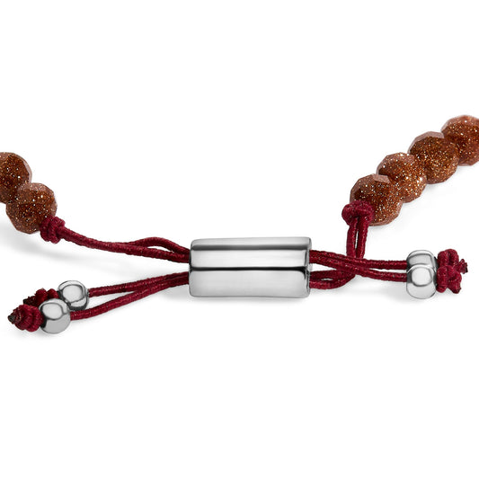 Close-up front angle of a white metal cylinder clasp bracelet with red cord and faceted brown gemstones on both sides.