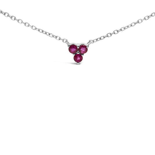 Close-up front view of a white necklace with a pendant featuring three round red gemstones arranged in a triangular cluster, shown on a white background.