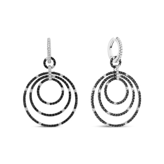Front-facing shot of a pair of white metal earrings featuring three concentric circles adorned with alternating black and white round gemstones in prong settings, with gemstone-studded hoop closures.