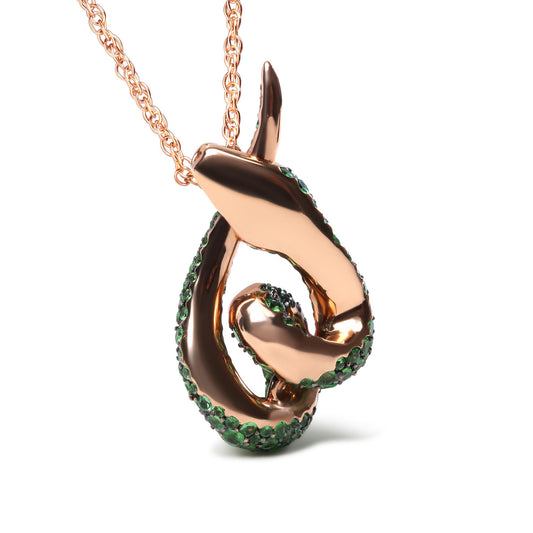 Close-up front angle of a rose metal abstract swirl necklace pendant adorned with small green gemstones in a pave setting.
