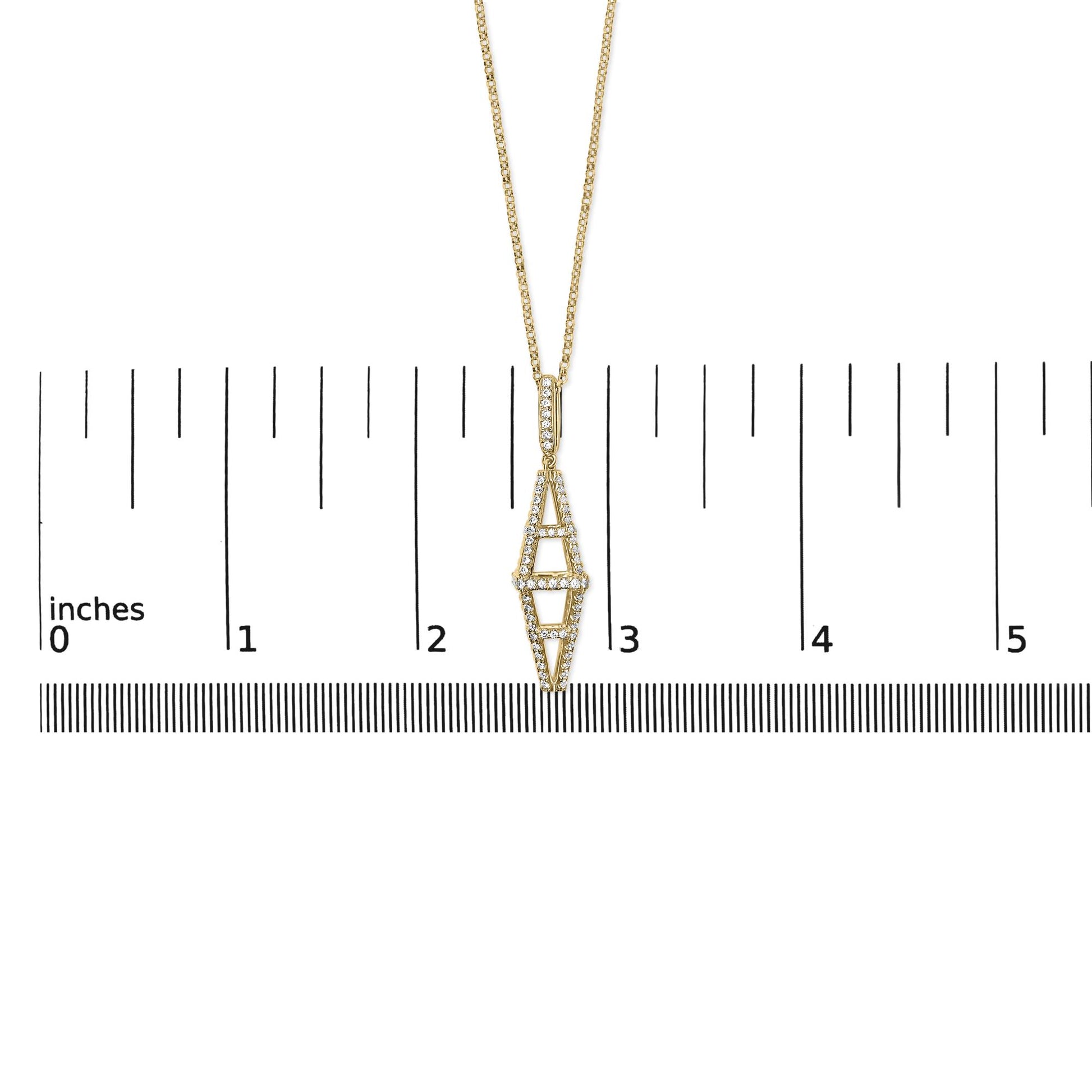 Yellow metal necklace with elongated geometric pendant featuring round white gemstones in pave setting, shown from front angle on ruler for size reference.